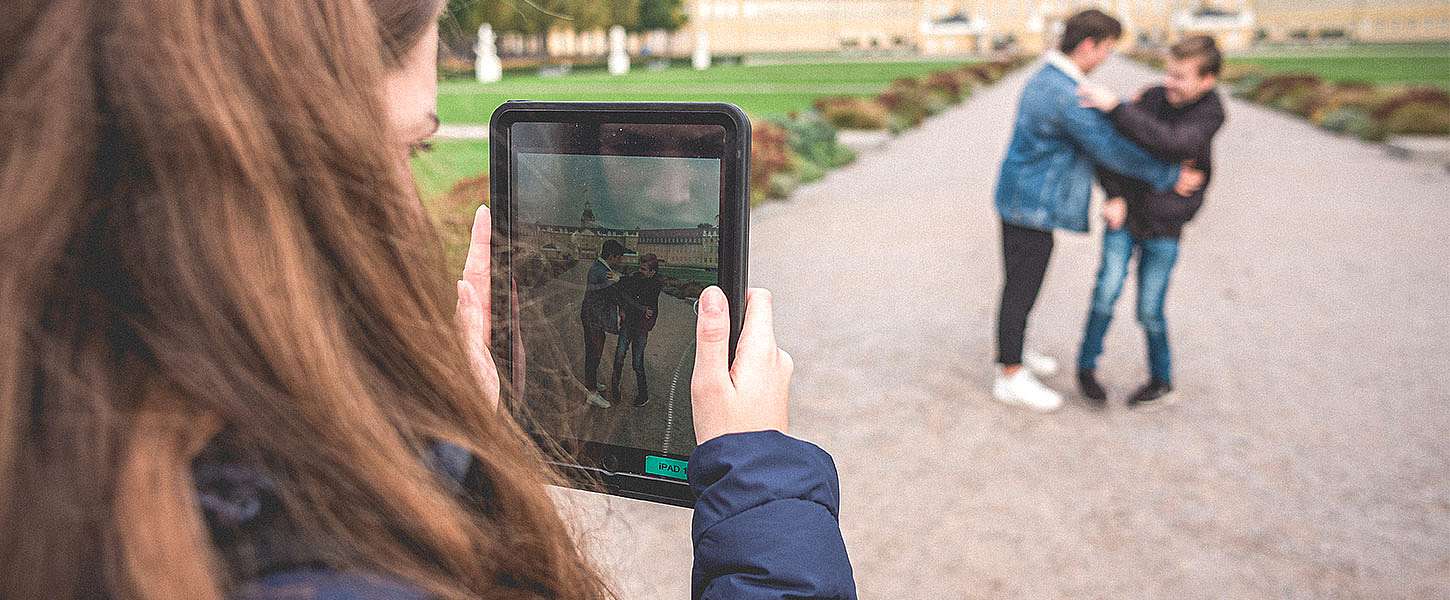 Zwei Jugendliche vor dem Karlsruher Schloss. Eine Jugendliche filmt die beiden mit einem Tablet.
