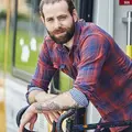 Ein junger Mann in karriertem Hemd lehnt sich aus einer Bahn heraus auf ein Fahrrad.