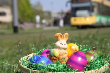 Korb mit Osterei und Schokohase, im Hintergrund fährt eine Trambahn