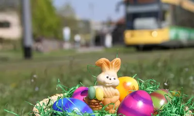 Korb mit Osterei und Schokohase, im Hintergrund fährt eine Trambahn