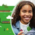 Mädchen lächelt in die Kamera und hält ihr Deutschlandticket in der Hand