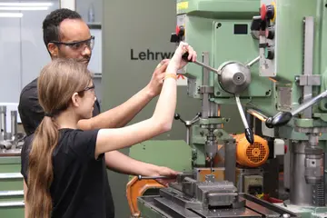 Ein Mitarbeiter der VBK mit einer Teilnehmerin am Girls' Day in der Lehrwerkstatt der VBK