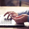 Zwei Hände tippen auf einer Laptop Tastaur. 