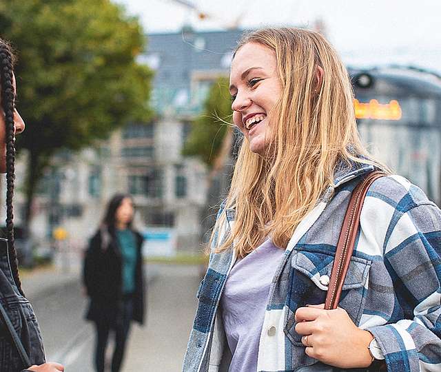 Zwei Teenager-Mädchen unterhalten sich an einer Bahnhaltestelle.