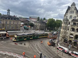 Eine Trambahn der Verkehrsbetriebe Karlsruhe passiert bei einer Testfahrt das erneuerte Gleisviereck an der Tullastraße. Im Hintergrund sind das Schlachthof-Areal und das Schloss Gottesaue zu sehen.