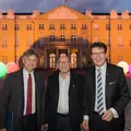Drei Männer in Anzügen stehen vor dem Karlsruher Schloss