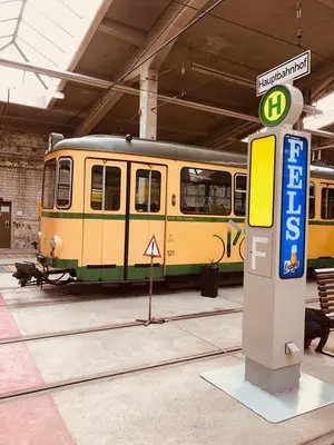 Eine alte Bahn in gelb-grün vor einem alten Haltestellenschild im Historischen Depot 1913 des TSNV.