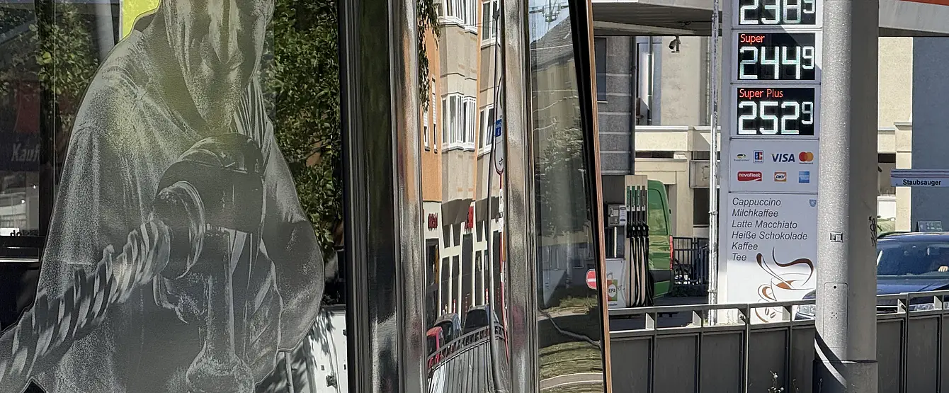 Das Foto zeigt die Preis-Säule an einer Tankstelle. Am linken Bildrand ist eine Straßenbahn zu sehen.