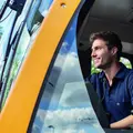 Ein Lokführer sitzt lächelnd in der Lokführerkabine einer Bahn.