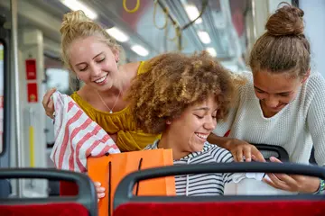 Drei Schüler*innen fahren mit einer Straßenbahn