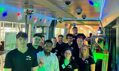 In einer bunt beleuchteten Bahn steht das VBK- und AVG-Team, das die Karaoke-Bahn organisiert hat. 