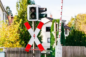 Auf dem Foto ist ein Bahnübergang mit Ampel, Andreaskreuz und Schranke. 