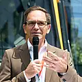 Der technische Geschäftsführer Christian Höglmeier steht vor einer Stadtbahn und spricht in ein Mikrofon.