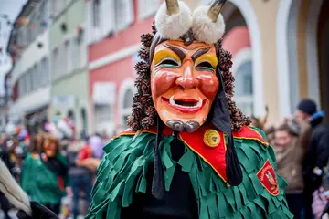 Ein verkleideter Narr mit einer Holzmaske