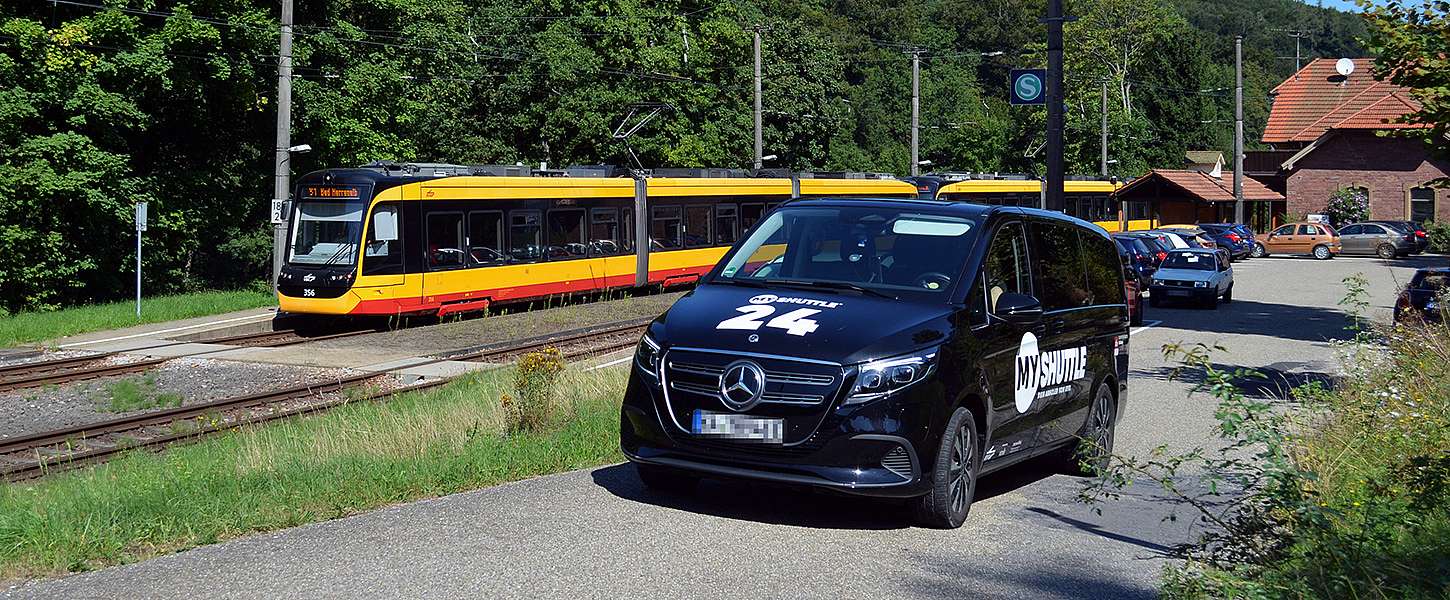 Das KVV.MyShuttle fährt neben einer KVV-Bahn.