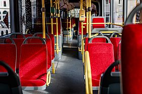 Rot gepolsterte Sitzreihen in einem Linienbus.