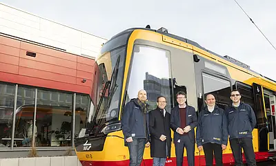 Vier Männer stehen vor dem gelb-rot lackierten VDV-TramTrain.