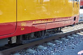 Gelb-roter Wagenkasten einer AVG-Stadtbahn und ein Schottergleis.