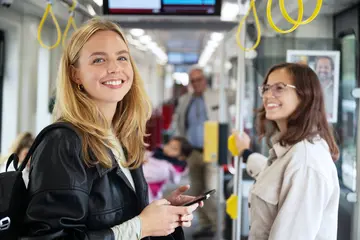 Zwei Junge Frauen stehen in einer straßenbahn und tragen keine Maske mehr