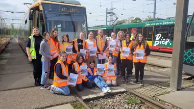 Schülerinnen, die am Girls' Day der VBK teilgenommen haben, stehe und sitzen vor einer Straßenbahn.