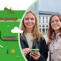 Zwei junge Frauen stehen draußen und lächeln freundlich in die Kamera.