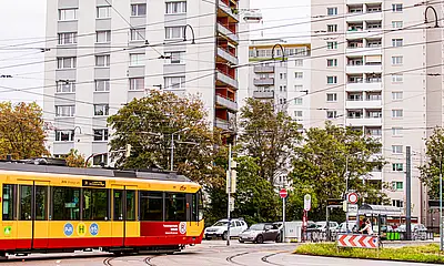 Eine Stadtbahn überquert den Kreuzungsbereich am Entenfang in Karlsruhe. Im Hintergrund sind weiße Hochhäuser und Autos zu sehen.