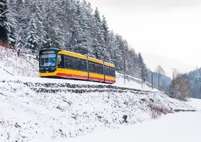 Eine AVG-Stadtbahn der Linie S1/S11 fährt durch das verschneite Albtal.