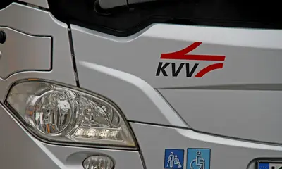 Scheinwerfer eines silbernen Busses mit KVV-Logo.