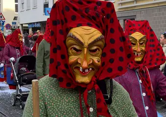 Das Symbolfoto zeigt eine Teilnehmer*in eines Fastnachtsumzuges mit einer Hexenmaske