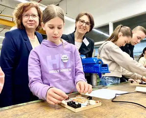 Staatssekretärin Dr. Ute Leidig (rechts) und VBK-Personalchefin Stephanie Schulze (links) schauen einer Teilnehmerin des Aktionstages im VBK-Betriebshof am Karlsruher Rheinhafen über die Schulter.