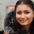 Eine junge Frau sitzt in der Bahn und lächelt.