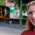 Vier junge Menschen sitzen auf einer Mauer. Zwei von ihnen schauen auf ihre Smartphones, einer auf ein Tablet und einer liest ein Buch.