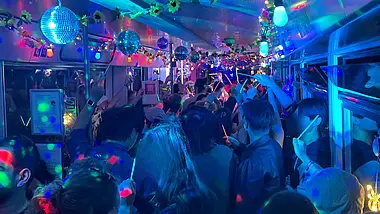 Partyatmosphäre mit bunten Lichtern in einer Bahn mit Menschen.