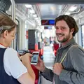Mann zeigt einer Kontrolleurin seine Fahrkarte auf dem Smartphone.