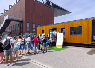 Besucher warten bei der Messe New Housing 2024 auf den Eintritt in ein Tiny House. 