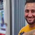 Ein junger Mann sitzt lächelnd in einer KVV-Bahn.