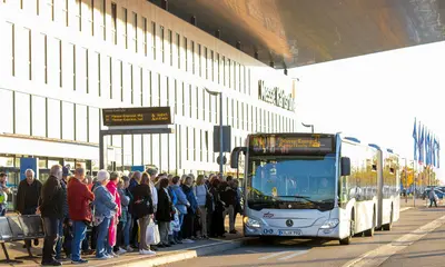 Ein VBK-Bus, der als Messe-Shuttle eingesetzt wird, steht vor der Messe Karlsruhe, an einer Haltestelle. Dort warten offerta-Besucher auf den Einstieg.