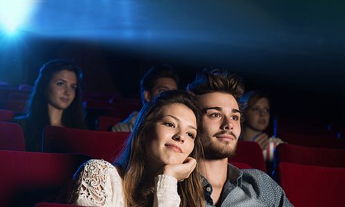 Mann und Frau in einem Kinosaal mit roten Sitzen.
