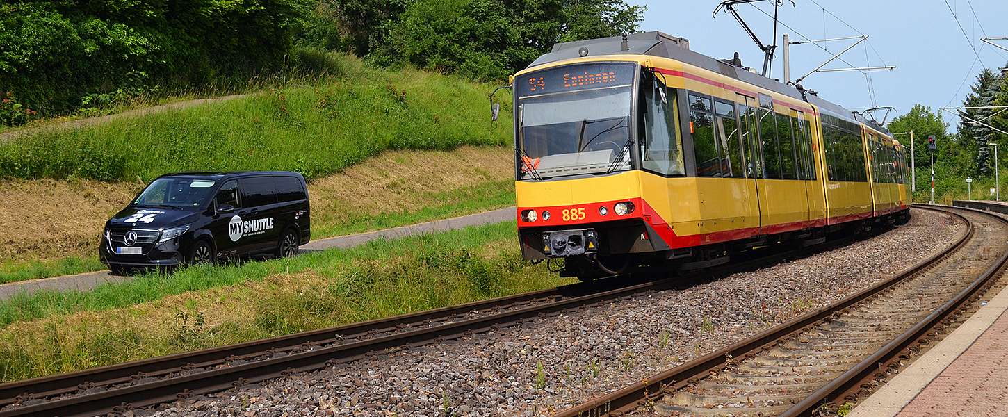 Das KVV.MyShuttle fährt neben einer KVV-Bahn.
