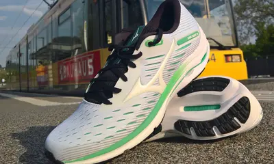 Ein Paar Laufschuhe liegt auf dem Bahnsteig einer Bahnhaltestelle. Im Hintergrund ist eine Straßenbahn zu sehen.