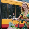 Eine junge Frau fährt mit einem KVV.nextbike an einer KVV-Bahn vorbei.