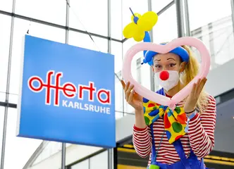 Ein Clown begrüßt Besucher*innen bei der Messe "offerta"
