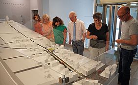 Mitarbeiter*innen des Stadtamtes Durlachs stehen am Modell der neuen Turmbergbahn.