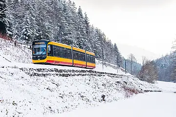 Das Symbolfoto zeigt eine Stadtbahn bei ihrer Fahrt durchs verschneite Albtal.
