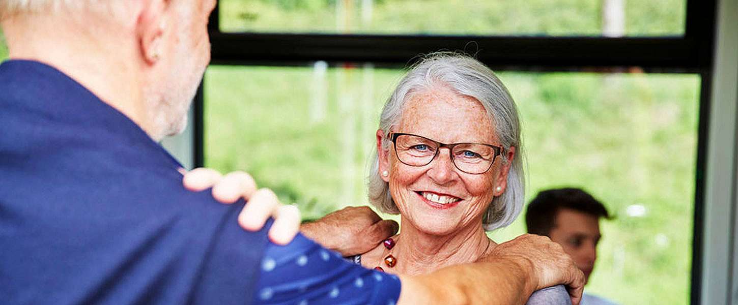 Eine Seniorin steht lächelnd in der Bahn.