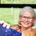 Eine Seniorin steht lächelnd in der Bahn.