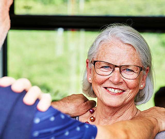 Eine Seniorin steht lächelnd in der Bahn.