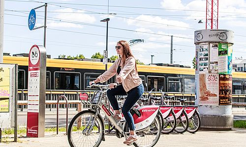 Eine Frau auf einem nextbike-Fahrrad. Im Hintergrund sieht man eine gelbe Straßenbahn