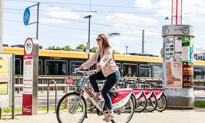 Eine Frau fährt auf einem Leih-Fahrrad von "KVV.nextbike". Im Hintergrund ist eine Straßenbahn zu sehen.