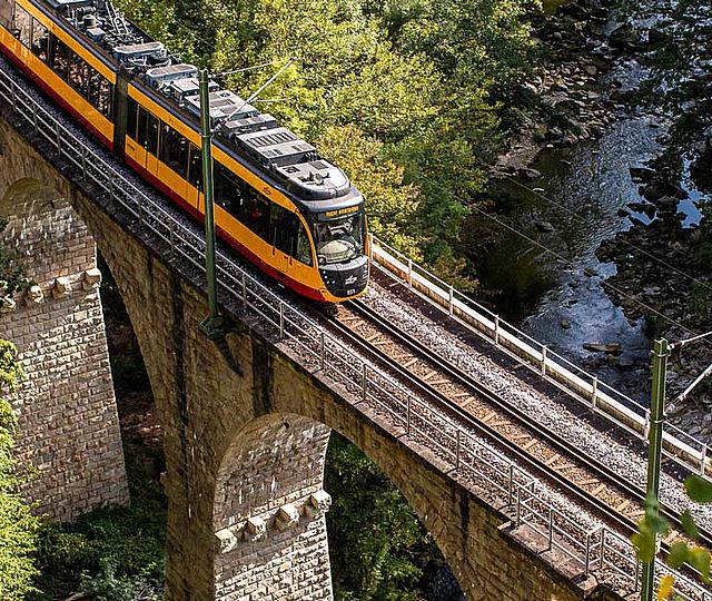 Eine Bahn der KVV fährt über ein Viadukt im Schwarzwald.